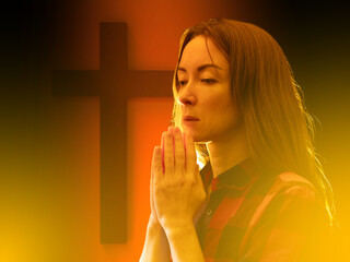Woman praying in front of Christian cross, surrounded by warm glowing light, expressing faith,...