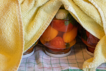 canning tomatoes at home, wrapping jars with warm cloth for slow cooling