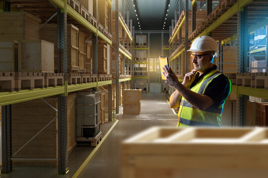 Man warehouse worker. Storekeeper with electronic tablet. Warehouse specialist at work. Industrial hangar with storage racks. Man warehouse manager thought. Storekeeper in uniform scratching his chin