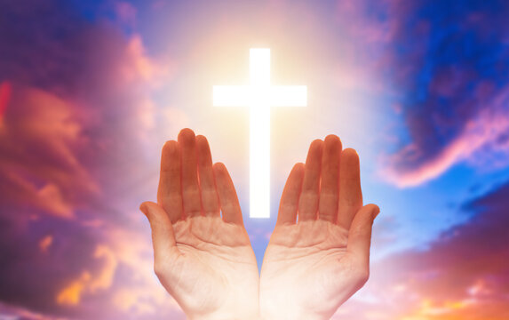 Christian religion. Catholic crucifix. Hands of believer. Christian cross glows in sky. Faith in god. Christian faith. Orthodox crucifix in clouds. Palms of person praying to god.