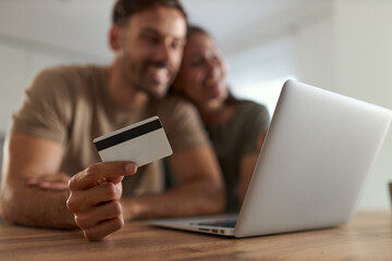 Close up of happy couple using credit card while shopping over computer at home.