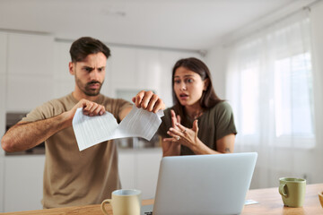 Close up of a couple tearing their tax bill at home.