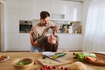 Happy mid adult couple having fun while dancing at dining room
