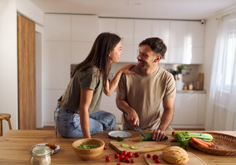 Young happy couple preparing food in the kitchen.	