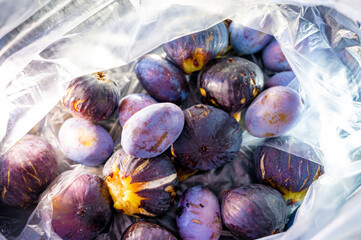 Close-up of blue figs and plums in a transparent plastic bag.