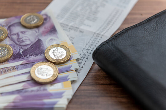 A UK cost of living concept with Sterling bank notes and coins, a grocery receipt and a purse.