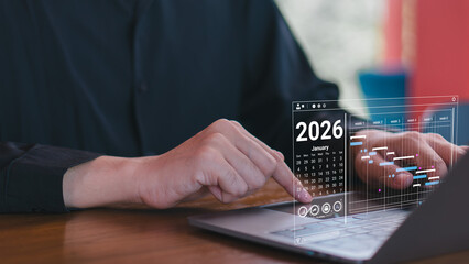 Man working on laptop with 2026 digital calendar and project planning chart, showing schedule, timeline, business management, and future strategy