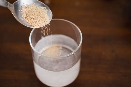 Adding yeast to glass of warm water with sugar