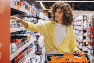 Woman Choosing Products in Supermarket with Shopping Cart