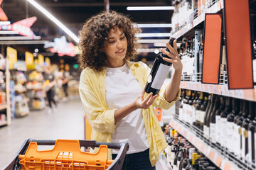 Young Woman Choosing Wine in Supermarket