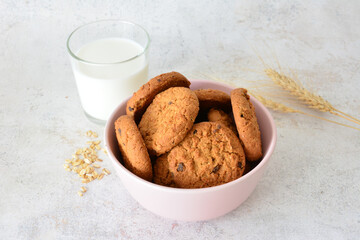 Delicious Oatmeal Cookies in bowl with Glass of Milk on pastel background