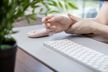 Person clutching painful wrist from extended computer mouse use, indicating a repetitive strain injury and ergonomic health concerns in modern digital workspace