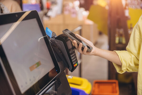 Customer using smartphone to pay at self checkout kiosk in supermarket - Powered by Adobe