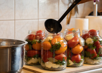 vegetables in a glass jar pour marinade to preserve tomatoes for the winter