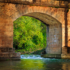 Small stone bridge on the edge of a river in Aveyron in the south of France in Ociitanie.