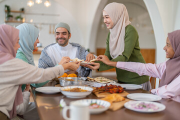 Muslim big family sharing traditional meal together around dining table wearing hijabs and kufi in cultural love, ramadan iftar celebration, eid al-fitr festive, halal meal gathering food culture