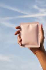 Small Pouch Packaging Held by Hand with Sky Background