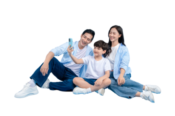 A family taking a selfie outdoors, with a warm and affectionate atmosphere. They are seated closely together, all looking at the phone. 