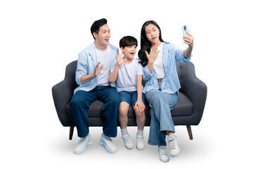Happy family waving during a video call. The parents and child are sitting on a sofa, creating a...
