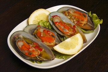Portugal. Succulent fresh mussels with salsa on a bed of lettuce with lemon garnish.