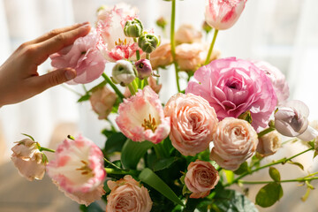 Person's hand gently touching delicate pink ranunculus bouquet showcasing tender care and appreciation for flowers