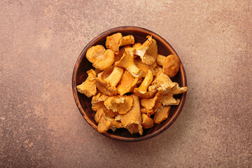 Fresh chanterelle mushrooms in a rustic wooden bowl, on a rustic brown background, a warm and inviting autumnal scene perfect for culinary uses
