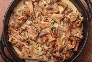 Close up of delicious chanterelle mushrooms frying in a creamy sauce with fresh dill and parsley,...