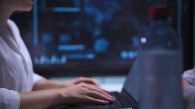 A woman typing on laptop at table opposite man in high tech office