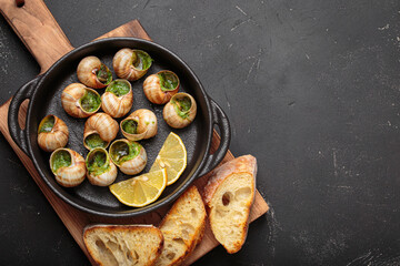Bourgogne snails baked with garlic and parsley butter, served in a cast iron pan on a wooden...