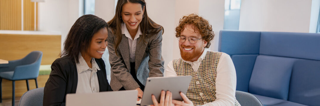 A diverse team works collaboratively using a digital device in a modern, contemporary workspace environment - Powered by Adobe