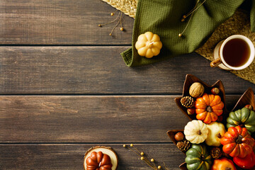 Autumn fall background with pumpkins, dry flowers, mug of tea, candles on rustic wooden table. Flat...