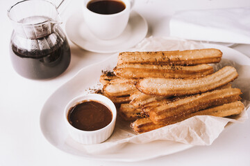 Traditional spanish treat street fast food churros on a plate with hot chocolate sauce.