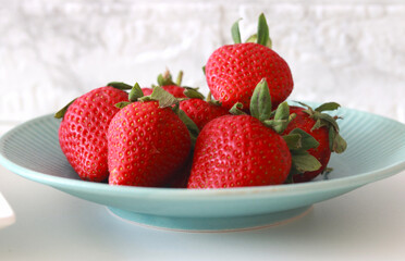 Fresh ripe strawberries served on a blue plate, perfect for healthy eating and food concepts.