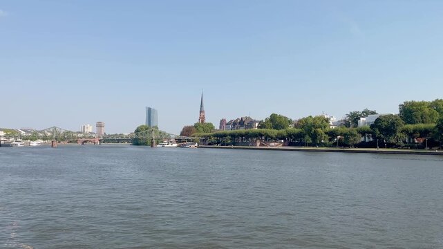Main river in Frankfurt in a sunny autumn day. Iron foot bridge called Eiserner Steg, historical church, trees and buildings are in the view