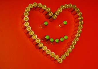 A heart-shaped arrangement of golden bullet casings with a smiling face made of green bullets,...