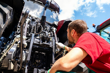 Low angle view of male agricultural machinery mechanic standing by farm tractor © Barillo_Images