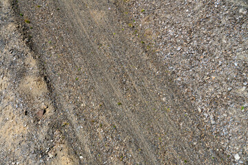 view from above on texture of gravel road with car tire tracks