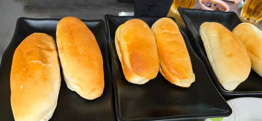 Vietnamese-style sandwiches are served on plate. Place two pieces on each plate. Baguette-influenced pastry that is crispy on outside and soft on inside. Cut in half and filled with various fillings.
