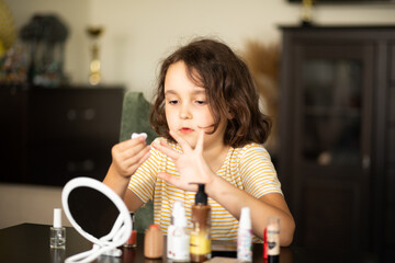 Cute little girl painting finger nails with polish. Kid doing manicure at home.