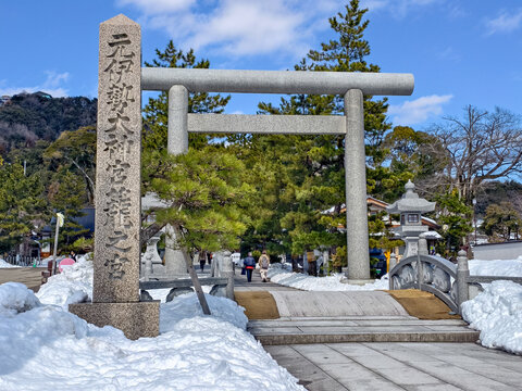 Miyazu, Kyoto, Japan - February 25, 2025 : The grand stone torii gate marking the entrance to the historic Motoise Kono Shrine, a significant Shinto site, covered in fresh snow.