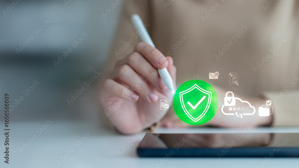 Poster close-up of hand using stylus with digital shield icon and cloud storage interface, symbolizing cybe