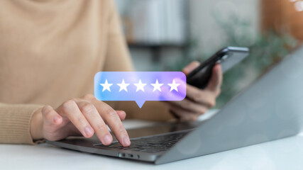 Close-up of hands using a laptop and smartphone with a five-star rating icon, symbolizing customer review, online feedback, and service satisfaction.