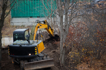 An excavator in the process of earthworks digs a pit for the future foundation.