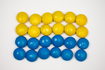Blue and yellow chocolate covered shell candy on white background resembling Ukrainian flag 