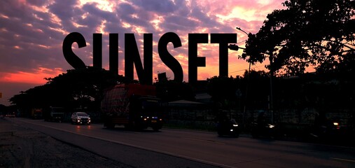 Scenic street view at sunset with a large SUNSET text overlay, a beautiful red sky and silhouettes of cars, trucks, and trees on the road.