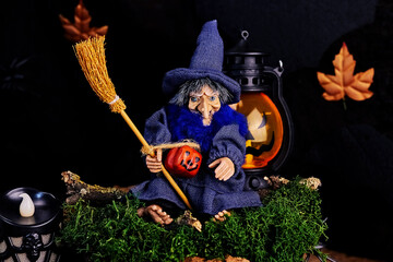 postcard with a smiling halloween witch sitting on a mossy stump with a broom and a jack o lantern