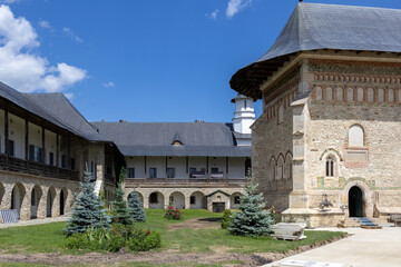 Fototapeta premium The courtyard of Voronet Monastery in Romania, featuring its historic stone walls, arched porticoes, and a tranquil garden