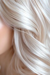 Naklejka premium Close-up of platinum blonde wavy hair showing silky smooth texture and natural shine against neutral background, highlighting professional hair care and styling results.