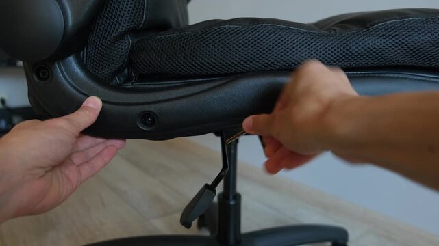 Tightening bolts on office chair close up hand using hex key furniture maintenance.