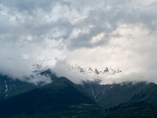 Mountain snowy peaks behind clouds